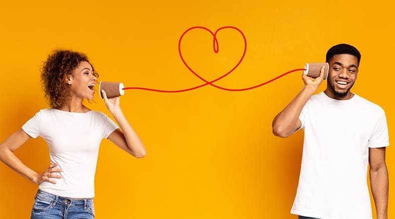 Young black couple with can phone on orange background